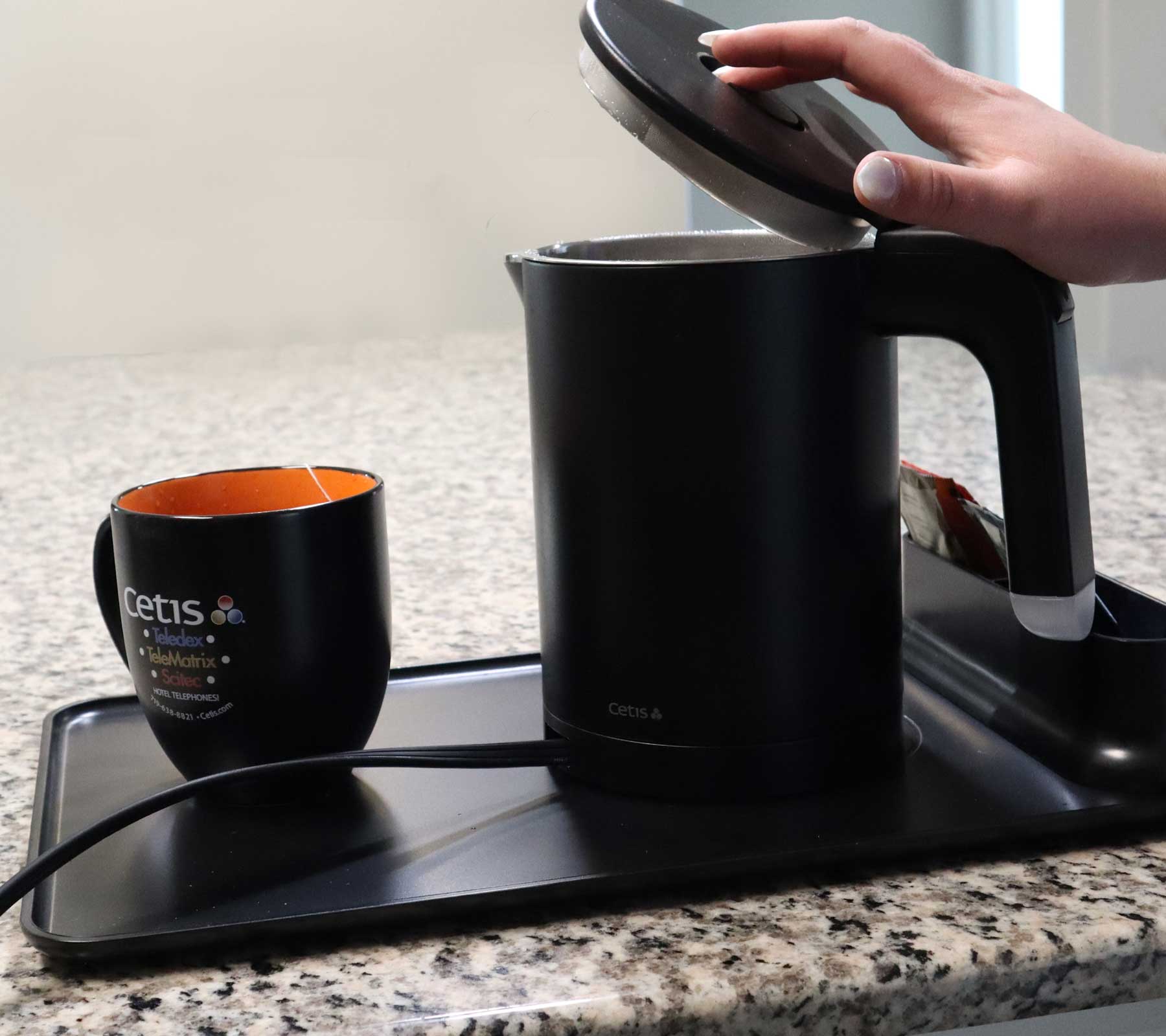 Valiant Products K-608 black electric kettle with anti-scalding insulation on a serving tray with a matching mug