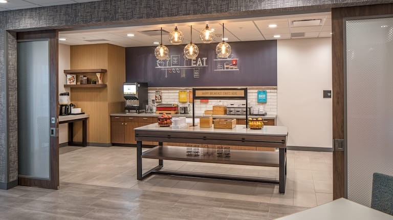 Valiant Products Luma 5-globe pendant light fixture with smoked grey glass shades and bronze finish in a hotel kitchen