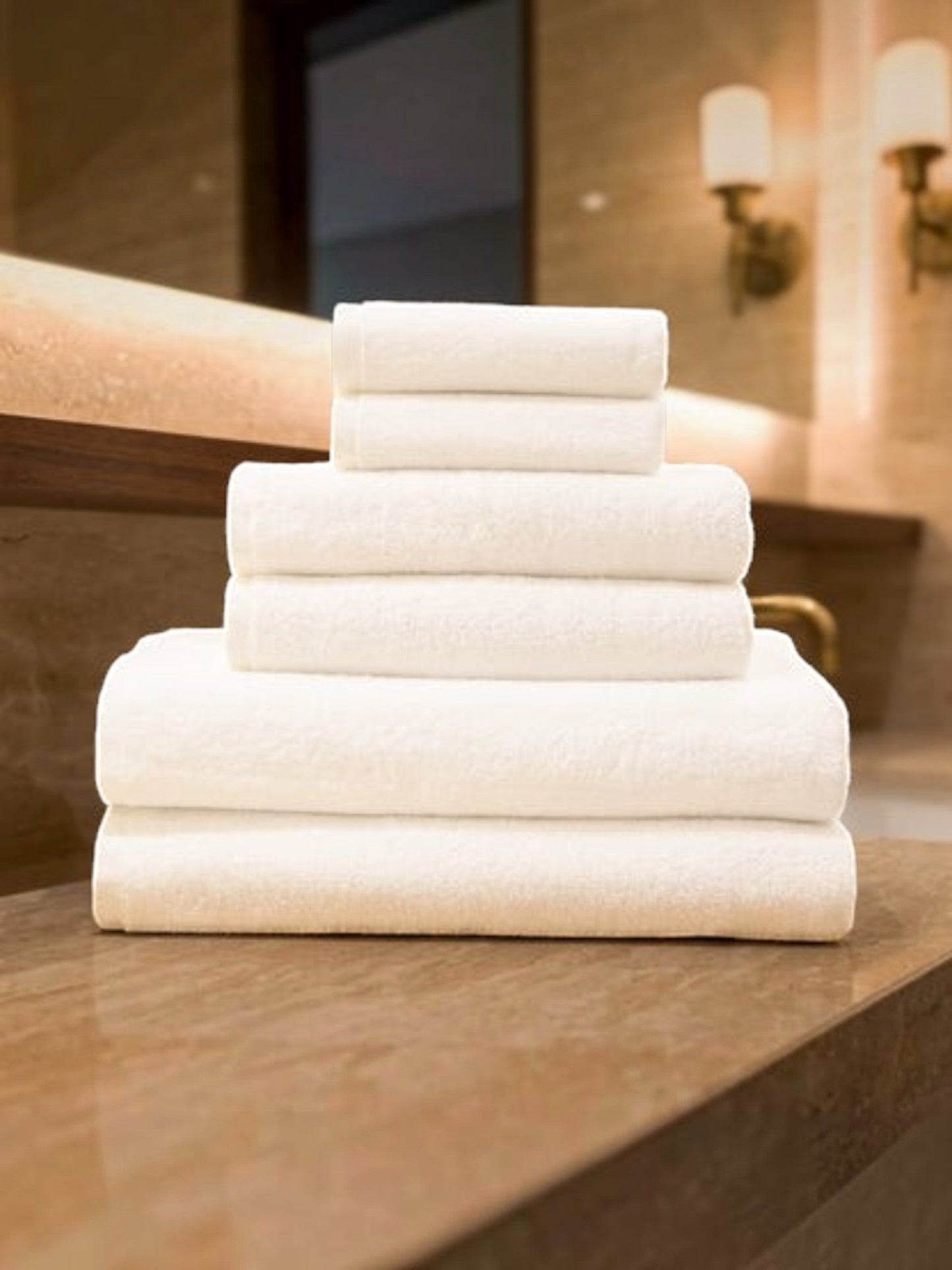 Valiant Products Luxe white borderless cotton hand towels stacked neatly on a bathroom vanity