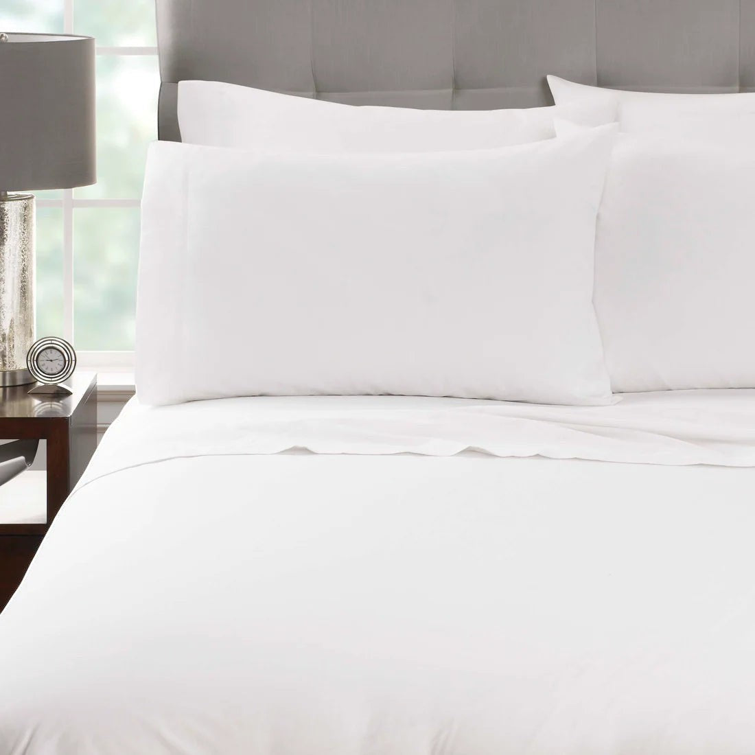 Valiant Products Millennium white percale fitted sheet and pillowcases on a made bed with a crisp cotton-blend finish.