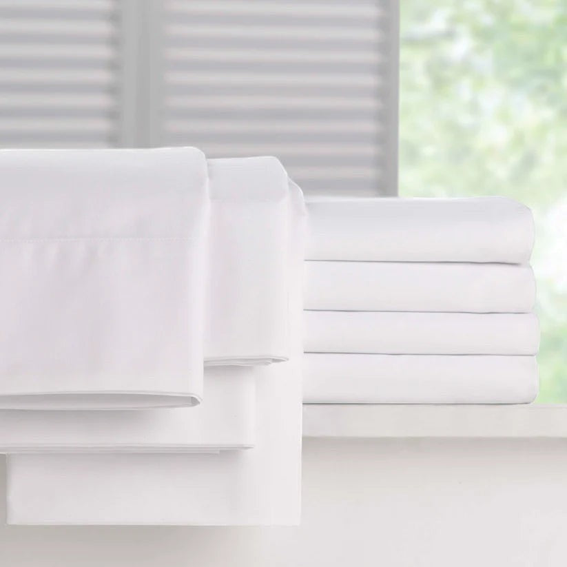 Valiant Products Millennium 250 thread count white cotton-blend pillowcases folded neatly in a bright bedroom setting.