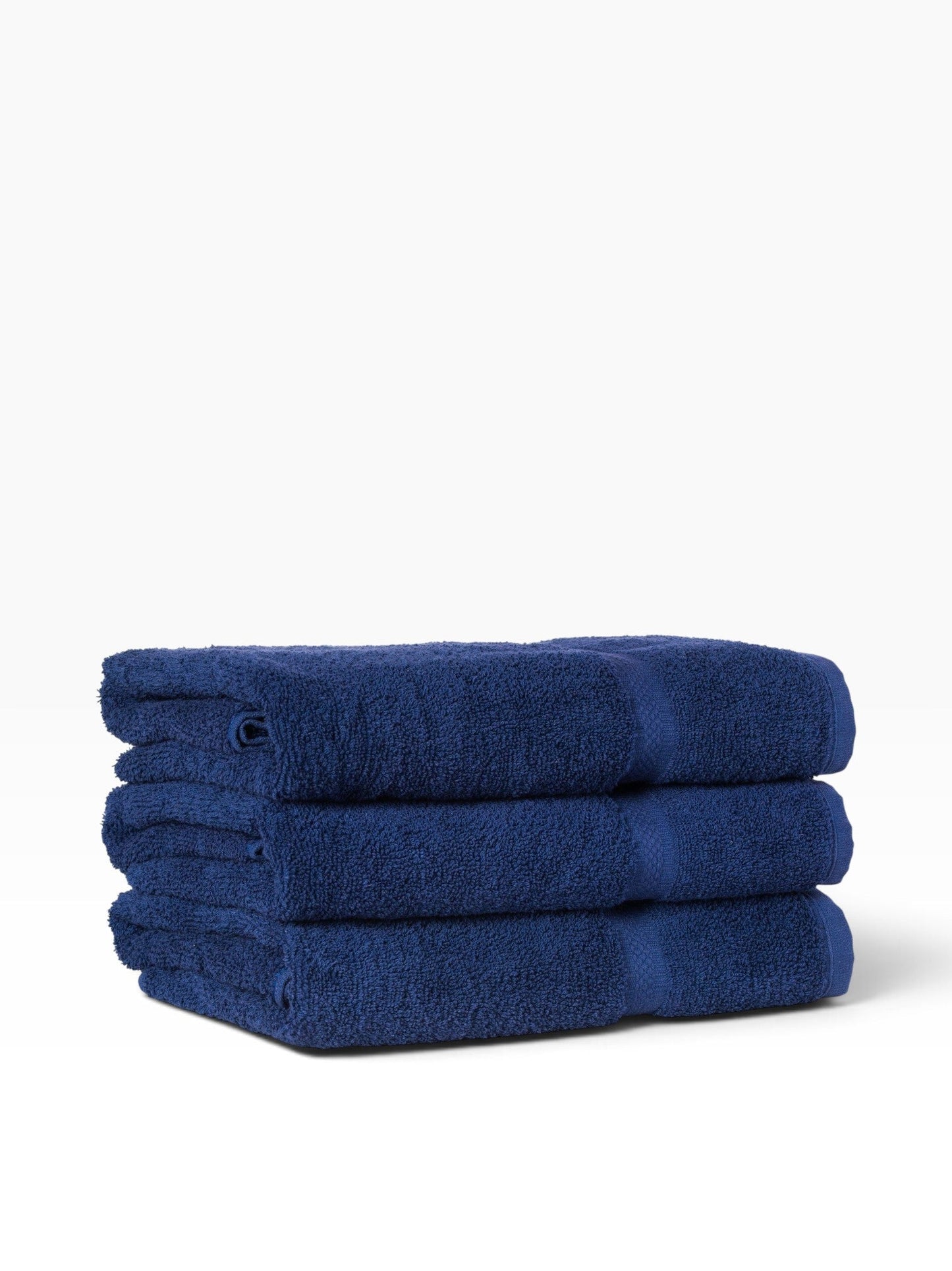 Valiant Products navy blue ring-spun cotton bath towels stacked with a decorative dobby border design.