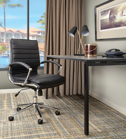 Valiant Products Themis mid-back black faux leather ergonomic office chair with chrome base and arms in a home office.