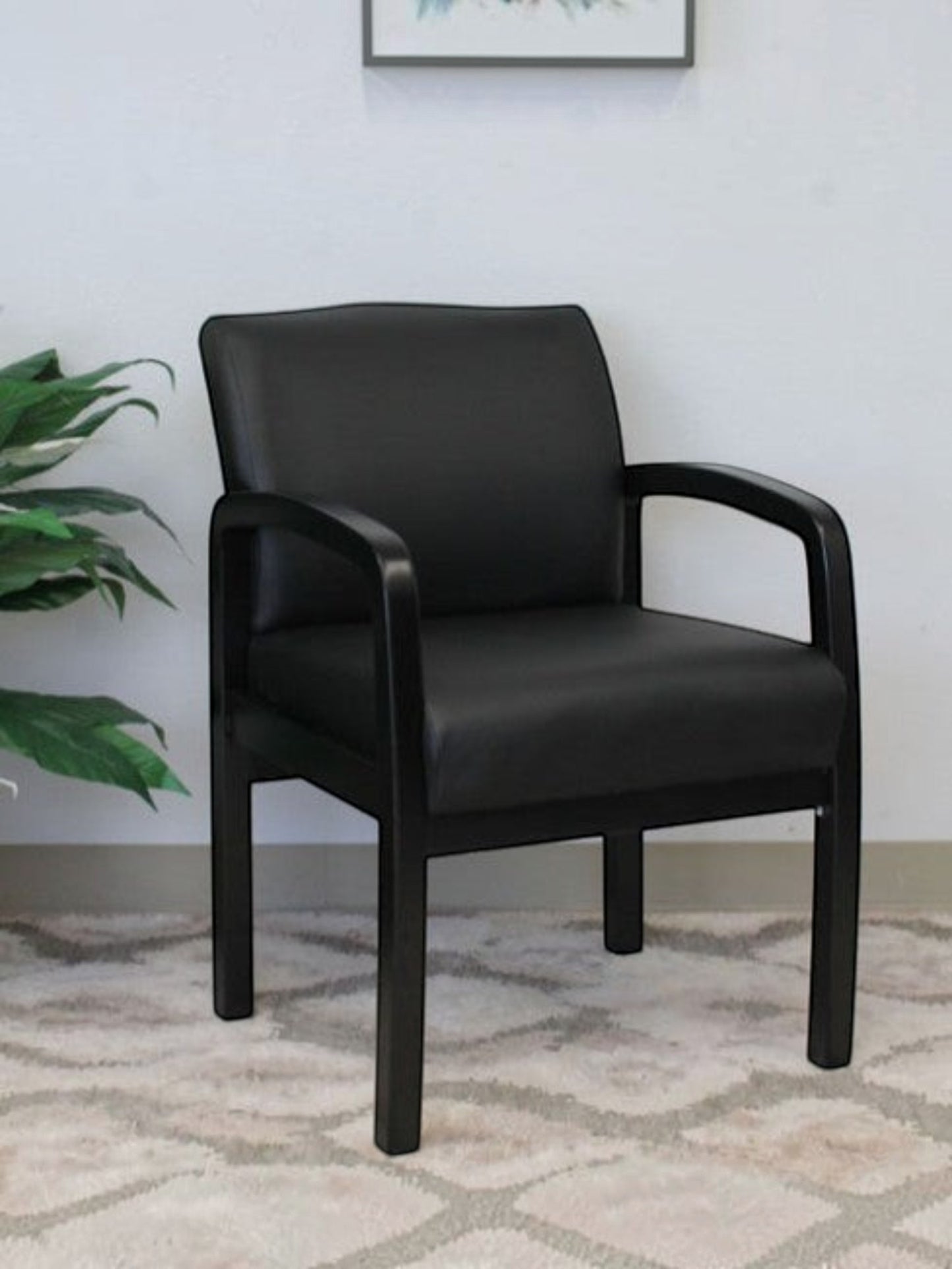 Valiant Products Tiernan guest chair with black antimicrobial vinyl upholstery and a sleek black wood frame.