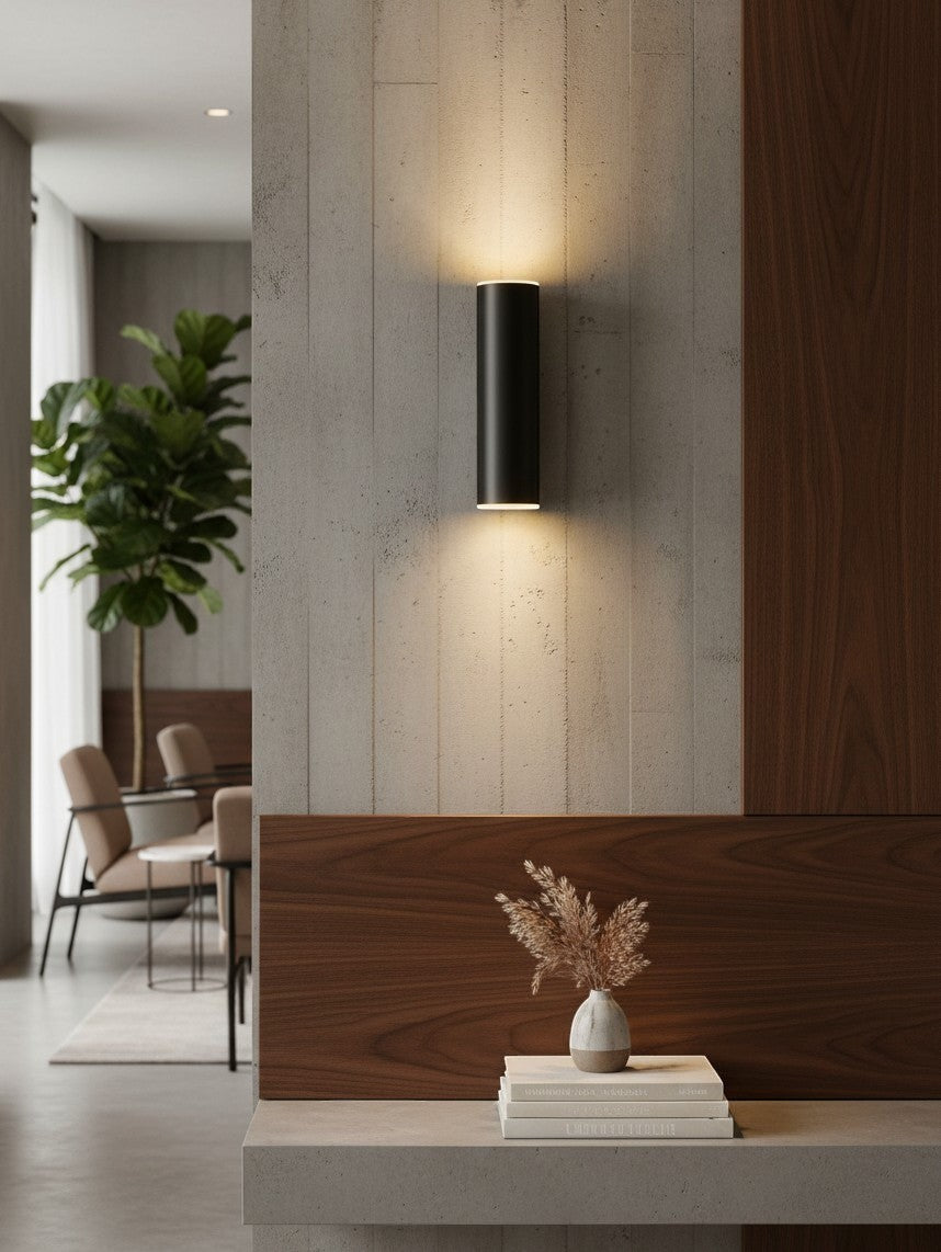 Valiant Products Totem matte black LED wall sconce casting warm up and down light on a textured concrete wall