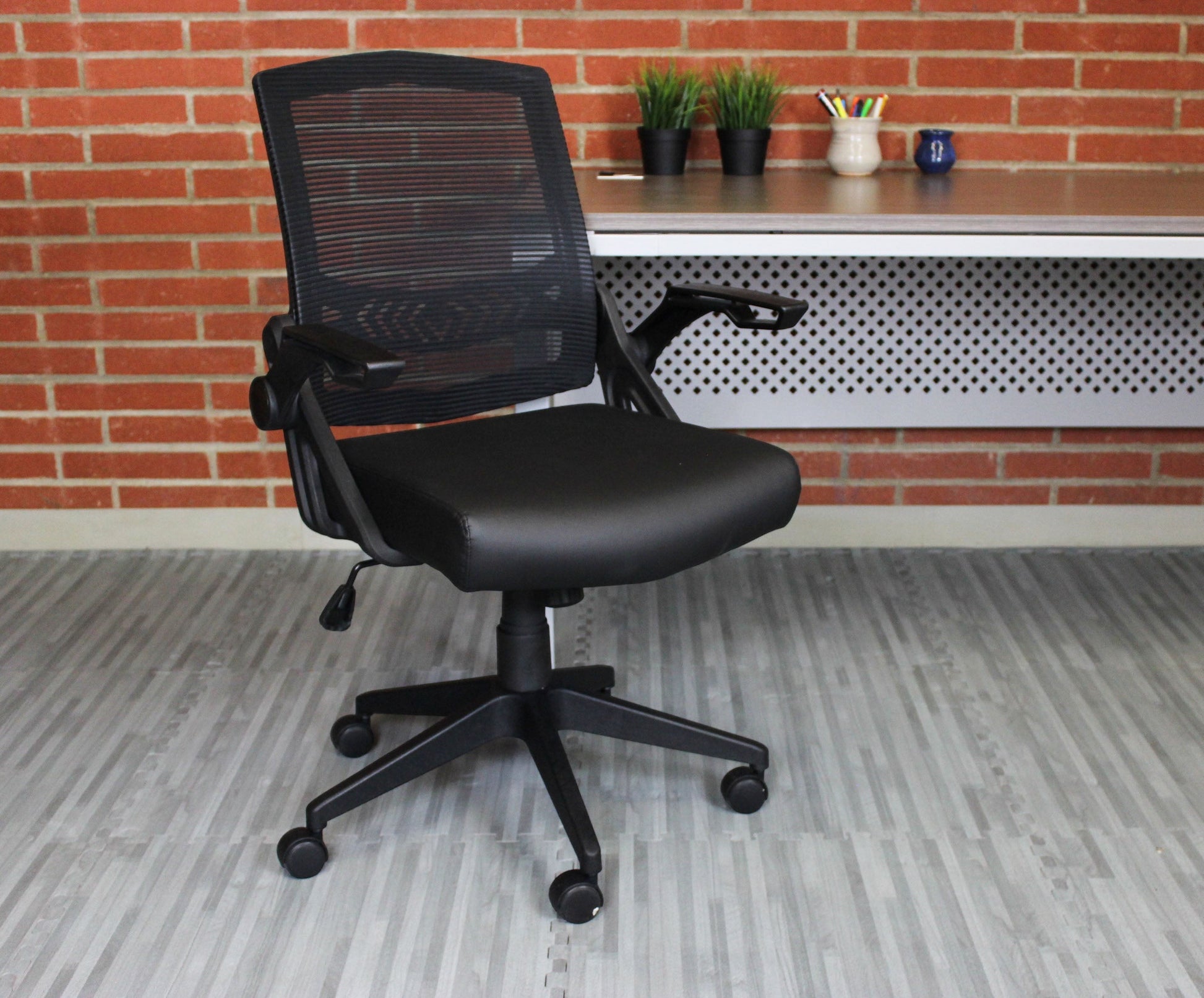 Valiant Products Tycoon ergonomic task chair with black mesh back, antimicrobial vinyl seat, and flip-up arms.