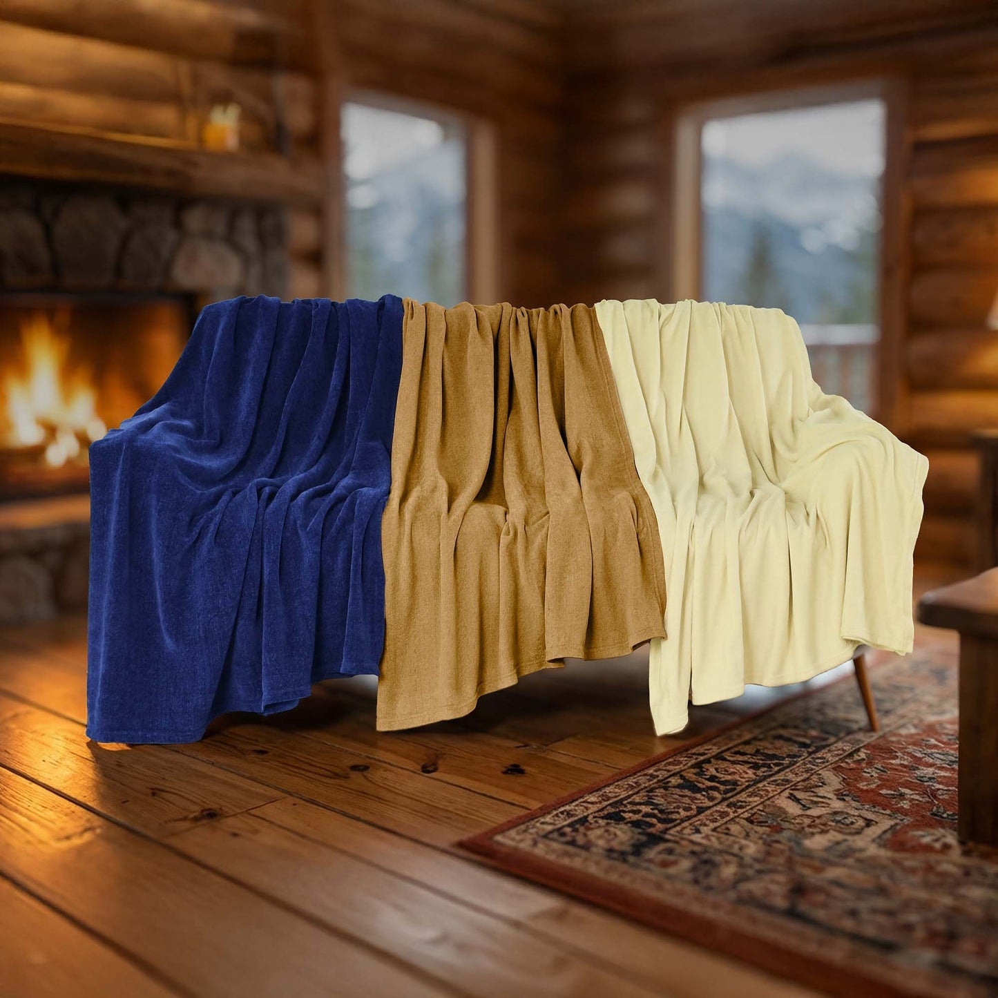 Valiant Products Vellux Renew polyester chenille blankets in navy, tan, and ivory draped over a sofa by a fireplace.