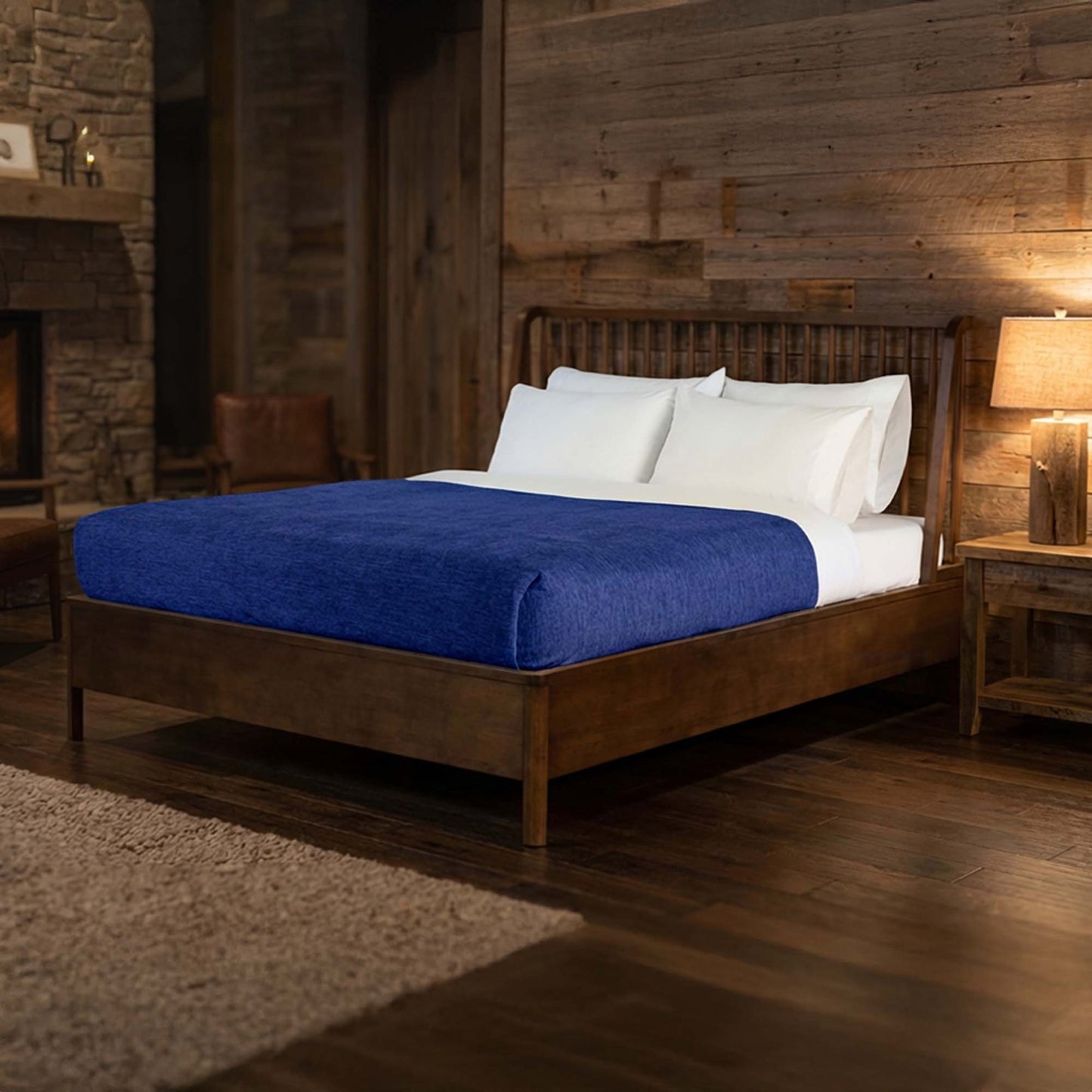 Valiant Products navy blue Vellux Renew polyester chenille blanket draped over a bed in a rustic hotel room.