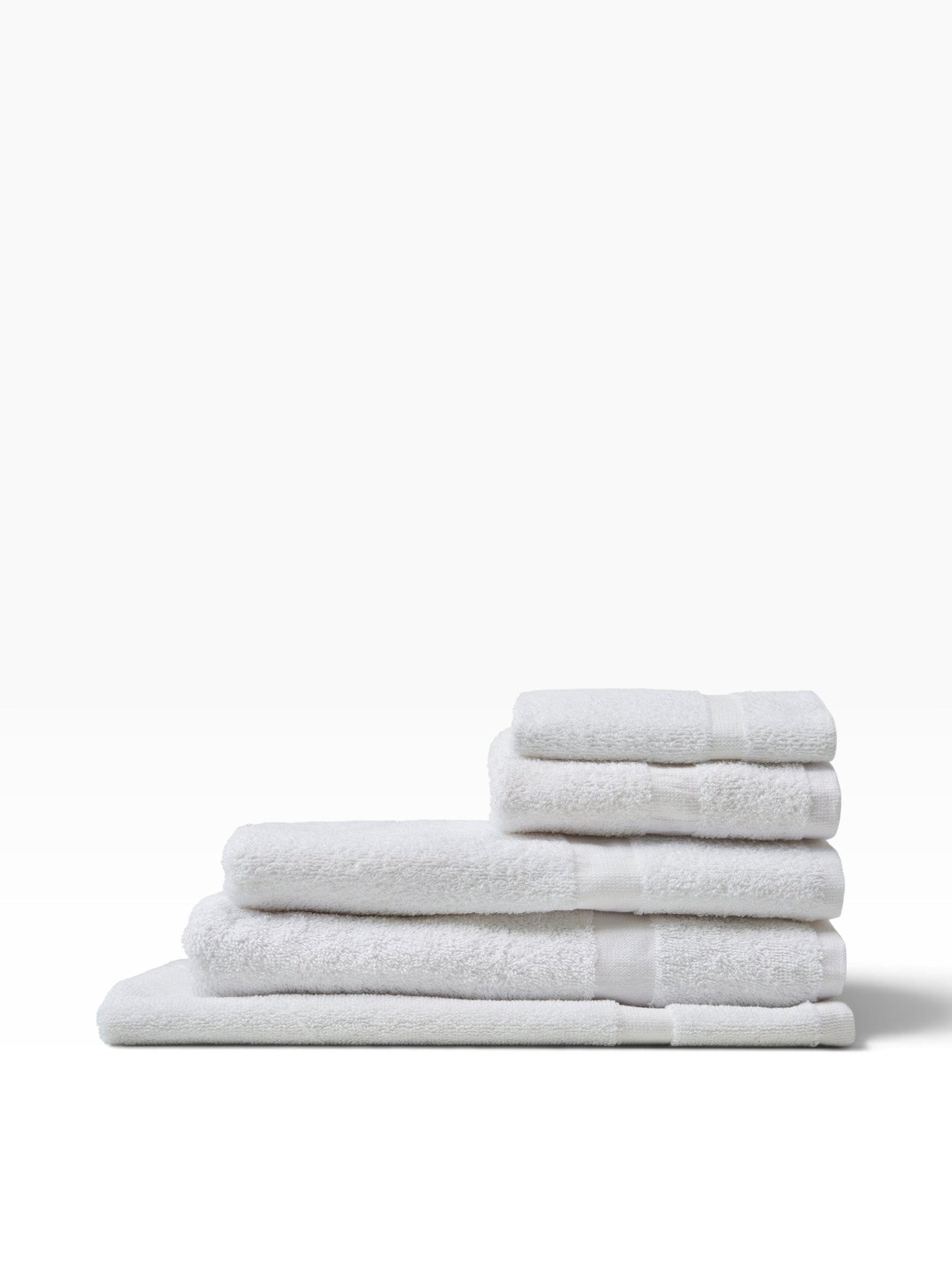 Valiant Products white cotton bath mats stacked neatly featuring a classic cam border design for commercial use