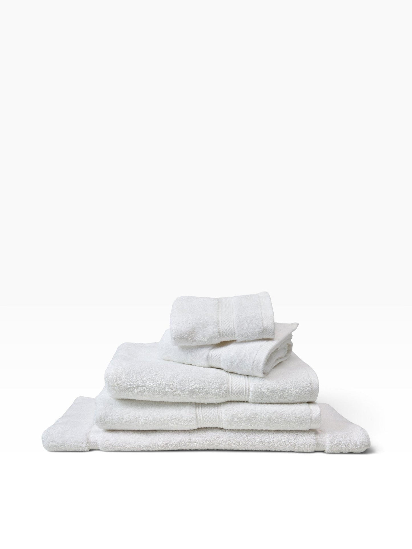 Valiant Products white plush cotton bath mats with textured dobby border design stacked neatly on a white background.