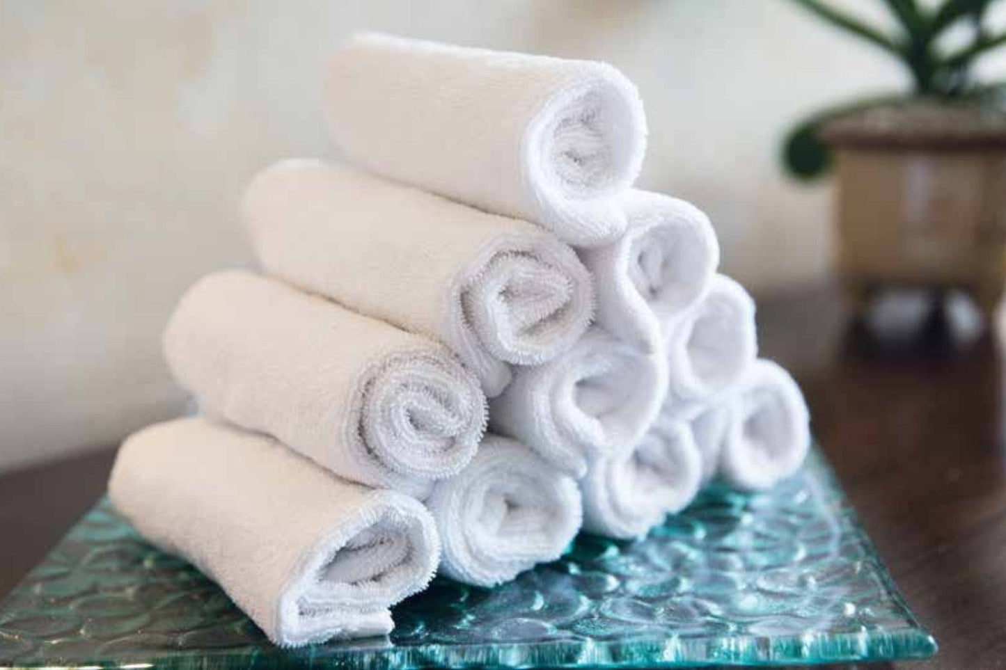 Valiant Products white cotton cam border bath mats rolled in a stack for commercial hospitality use