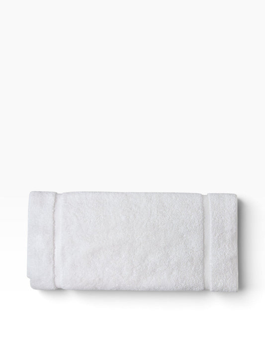 Valiant Products white plush cotton bath mat with a textured dobby border design, folded for a clean look.