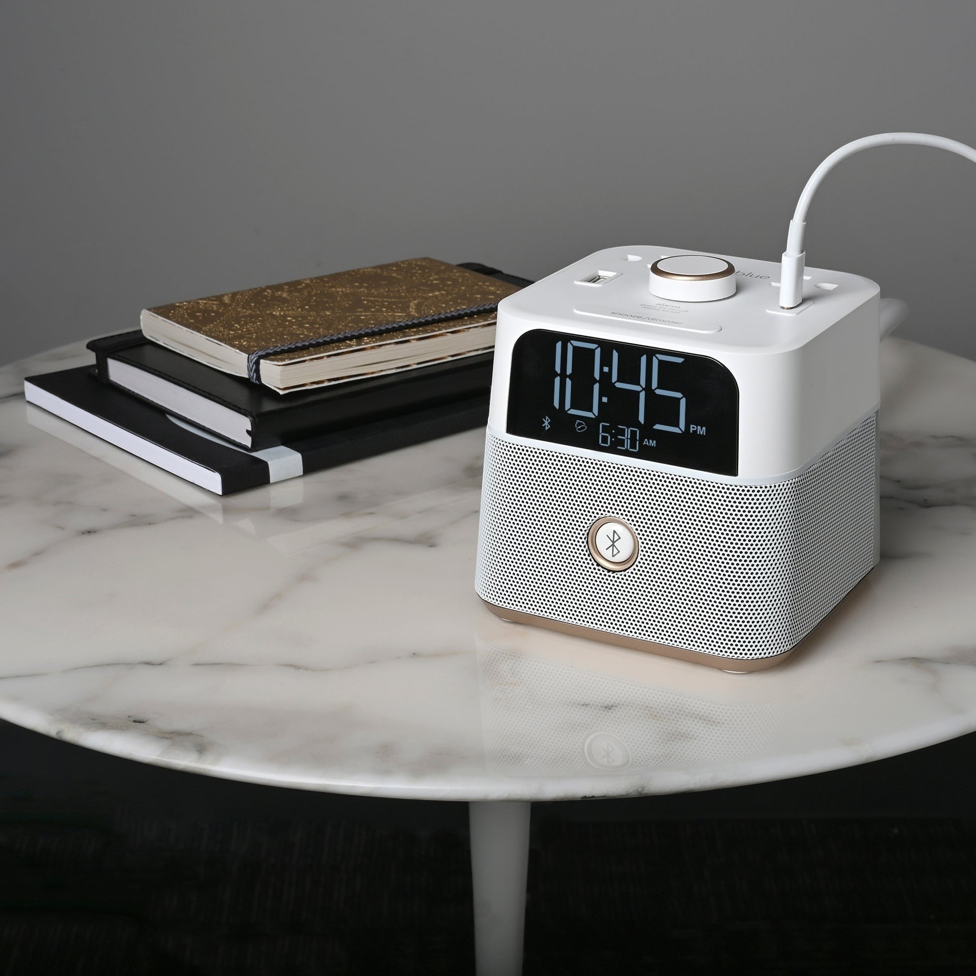 Valiant Products white CubieBlue alarm clock with Bluetooth speaker, USB ports, and digital display on marble table.