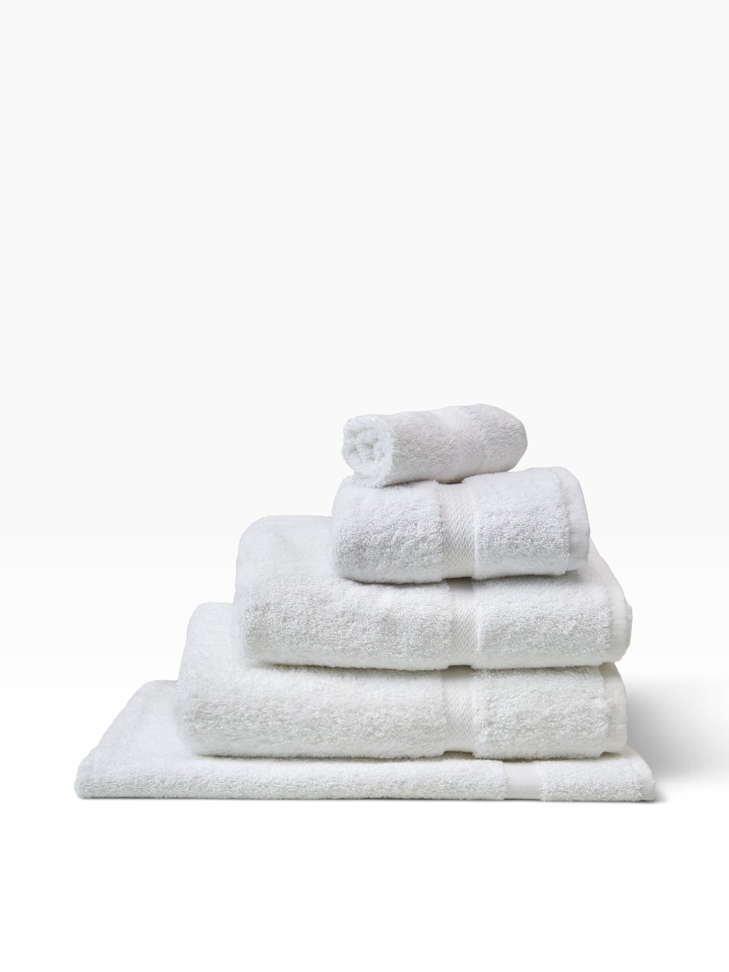 Valiant Products white Royal Suite Dobby border bath towels stacked neatly, featuring soft ring-spun cotton loops.