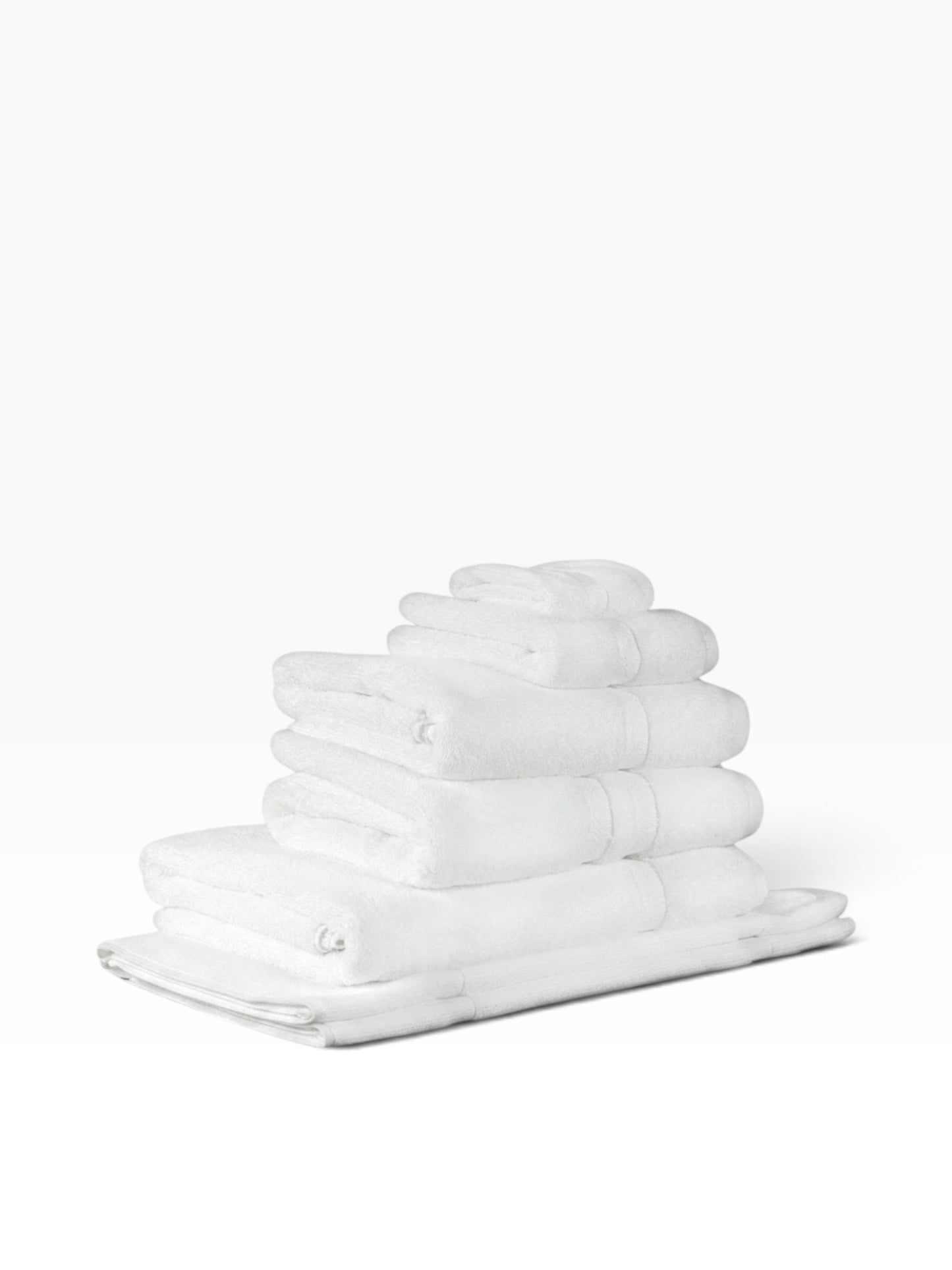 Valiant Products white Simplicity dobby border bath towels stacked neatly, featuring soft cotton loops.