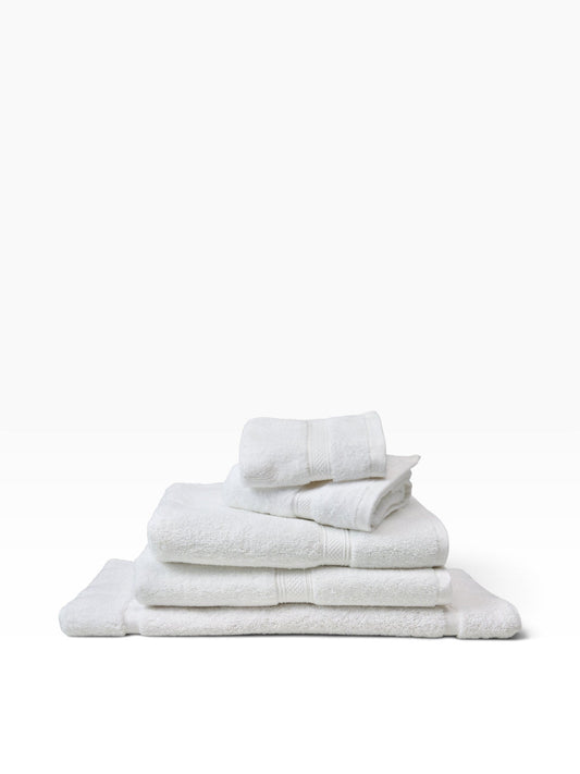 Valiant Products white plush dobby border hand towels stacked neatly, made from a durable cotton-polyester blend.