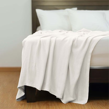 Valiant Products Atelier Luxe white cotton and TENCEL Modal blanket with a refined herringbone weave on a bed.