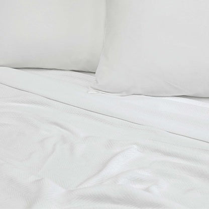 Valiant Products white Atelier Luxe blanket featuring a soft herringbone weave texture on a made bed with pillows.