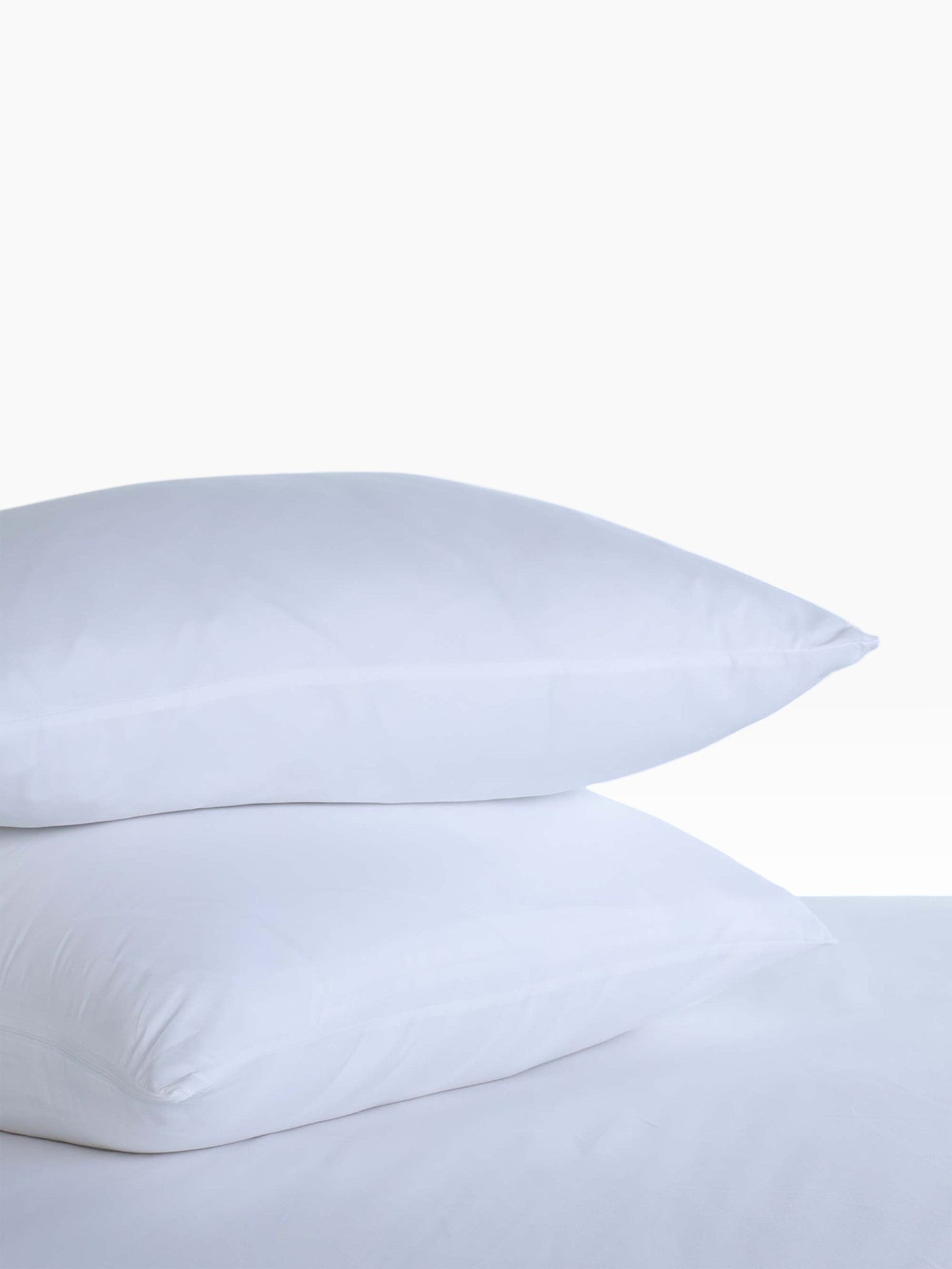 Valiant Products white microfiber pillow protectors stacked on a bed for hospitality use