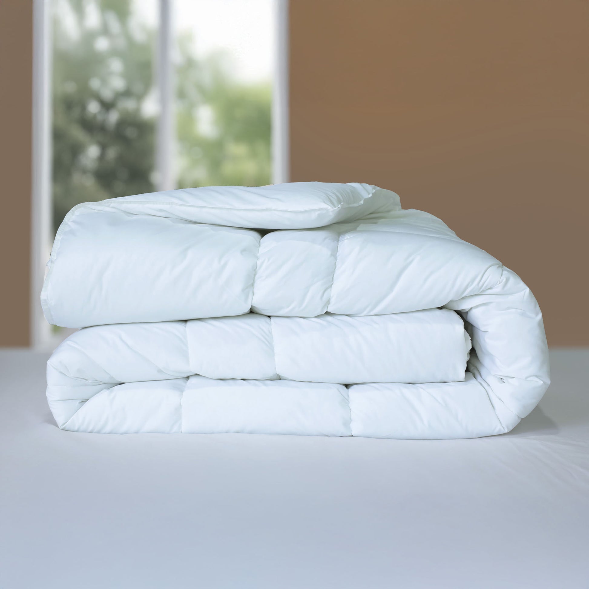 Valiant Products white down alternative quilted comforter with box stitching and corded edges on a bed