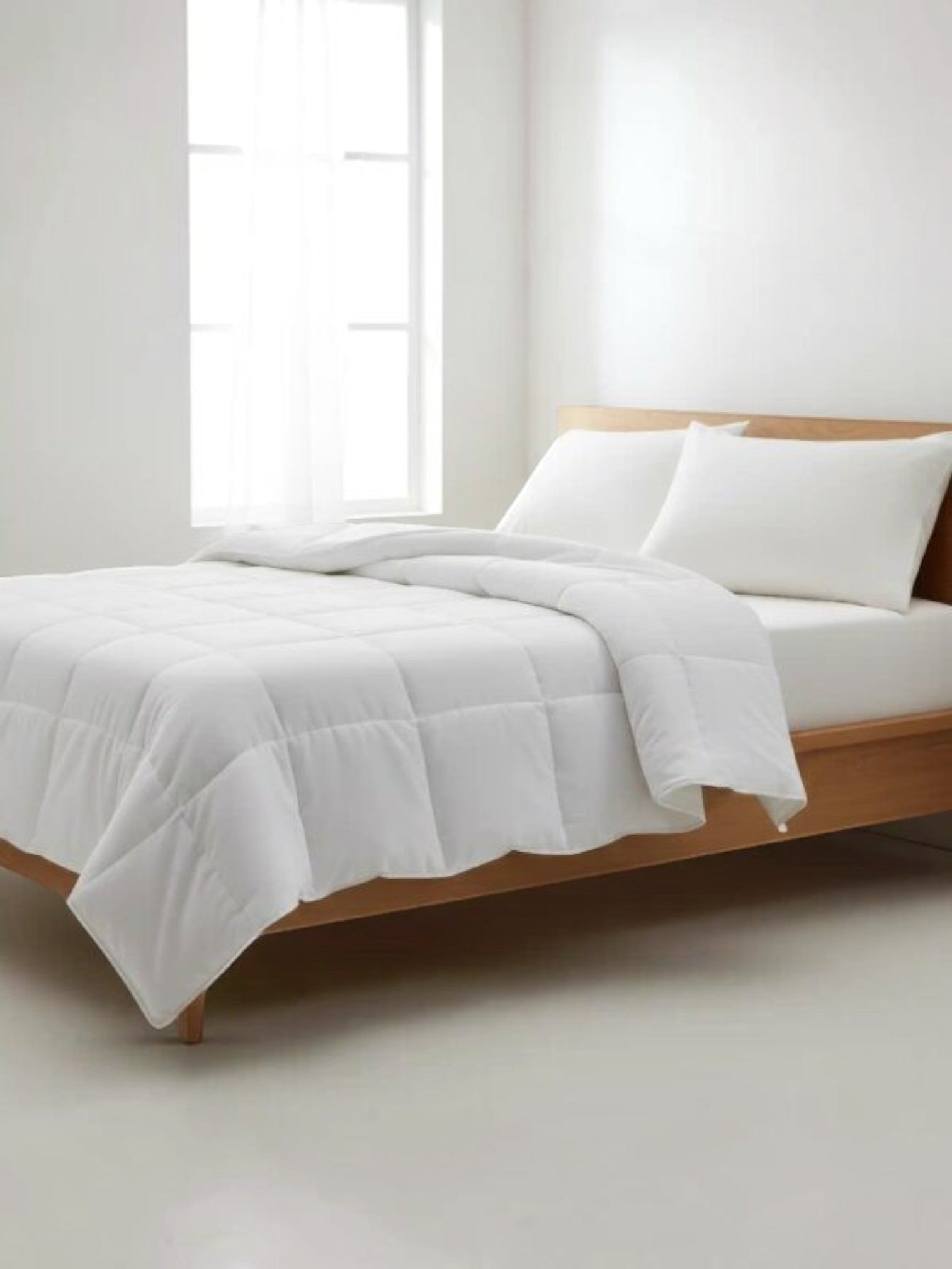 Valiant Products white down alternative comforter with box stitch quilting on a wooden bed frame in a bright bedroom.