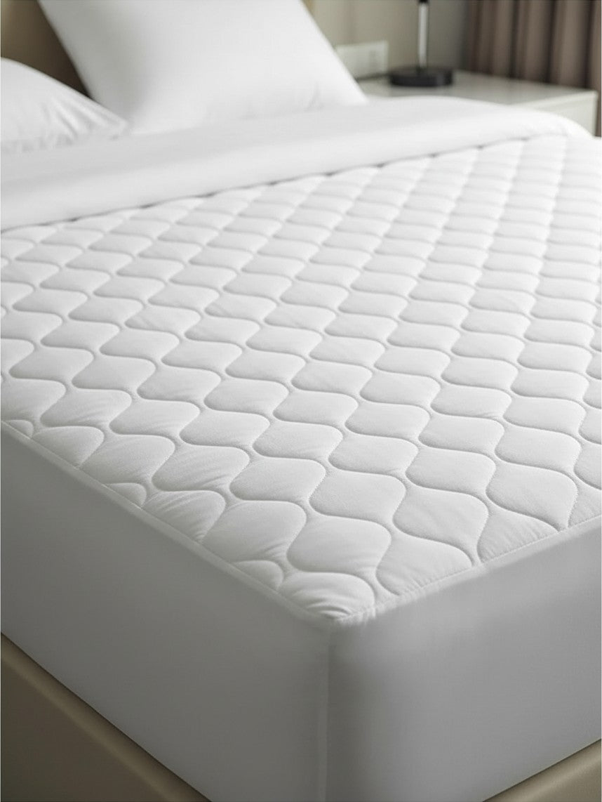 Valiant Products Ultra Touch white microfiber mattress pad with an elegant ogee quilted pattern on a made bed.