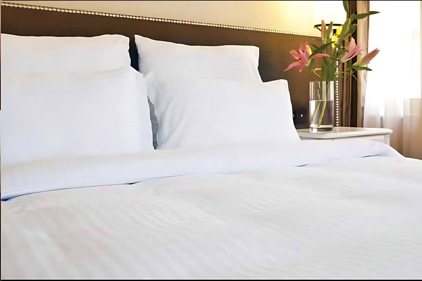 Valiant Products Royal Suite white cotton-blend pillowcases with subtle satin stripes on a neatly made hotel bed.